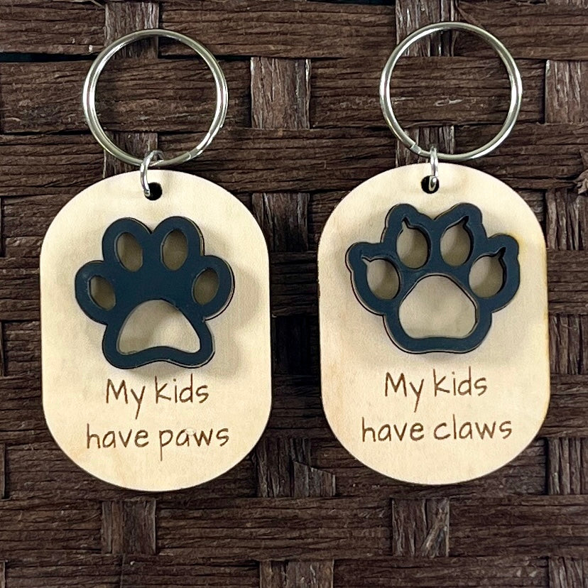 My Kids Have Paws and My Kids Have Claws maple keychains with black acrylic paw print and claw on dark background