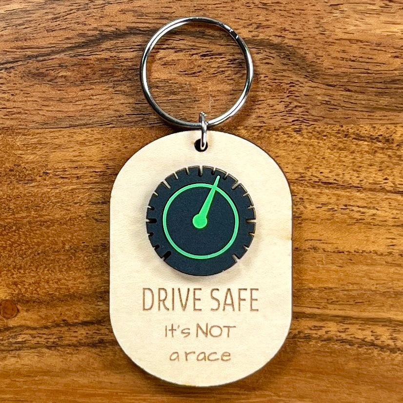Drive Safe It's Not a Race laser-engraved maple keychain with black and green acrylic speedometer