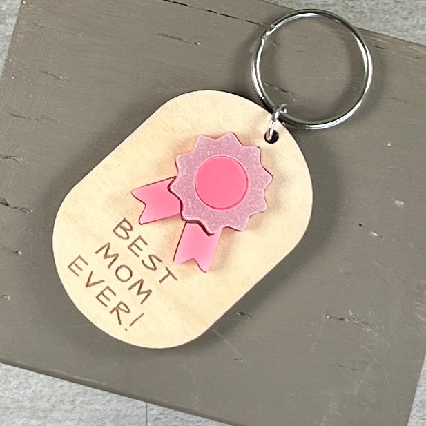 Best Mom Ever acrylic daisy keychain in pink on natural maple wood with key ring.
