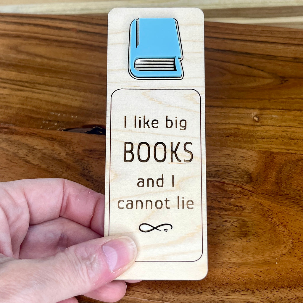 Hand holding I Like Big Books and I Cannot Lie birch bookmark showing eucalyptus acrylic book detail