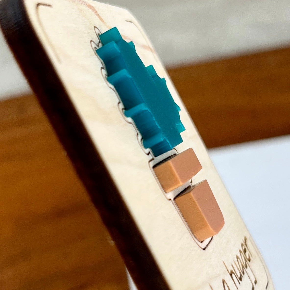 Side view of Not a Hugger plant stake showing layered maple wood and teal acrylic cactus depth
