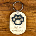 My Kids Have Claws laser-engraved maple wood keychain with black acrylic claw on wood background