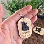 Hand holding Life Is Better With Cats maple keychain showing black acrylic cat duo silhouette detail