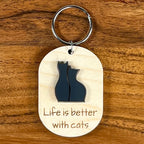 Life Is Better With Cats laser-engraved maple wood keychain with black acrylic cat duo silhouette on wood background