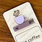 Close up of Sip Coffee Read Books Stay Cozy birch bookmark showing ash rose coffee cup on mauve acrylic book