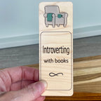 Hand holding Introverting with Books birch bookmark showing sage acrylic chair and mug detail