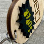 Side view of Super Dad maple wood keychain with black and yellow acrylic comic burst.