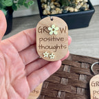 Hand holding Grow Positive Thoughts laser-engraved maple keychain with lemon acrylic flowers