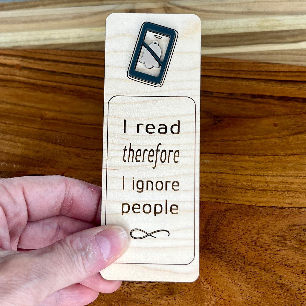 and holding I Read Therefore I Ignore People birch bookmark showing charcoal acrylic detail