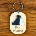 Oval wooden keychain with black and white acrylic dog and cat, engraved 'Fur Mama,' on a wood surface with a metal split ring.