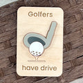 A rectangular wooden golf-themed magnet with rounded corners, laser-engraved with the words 'Golfers have drive' and a stylized acrylic golf club and ball design. The sign is placed on a brown woven wicker surface.