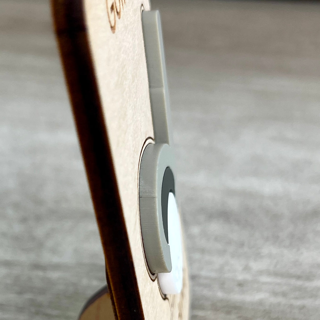 Close-up side view of a light wood magnet with a layered gray and white acrylic golf club and ball layer, photographed against a blurred gray surface and designed to highlight the 3D effect of the acrylic.
