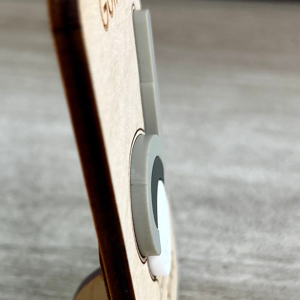 Close-up side view of a light wood magnet with a layered gray and white acrylic golf club and ball layer, photographed against a blurred gray surface and designed to highlight the 3D effect of the acrylic.