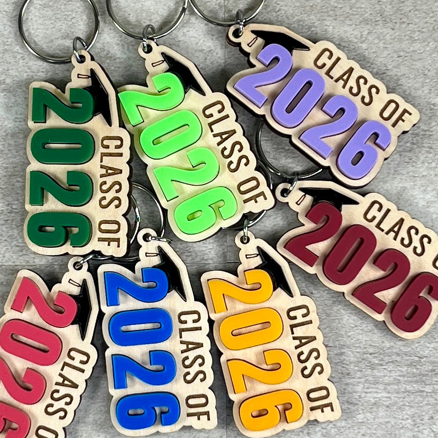 Collection of Class of 2026 maple keychains with acrylic grad caps in assorted colours including green, purple, pink and red