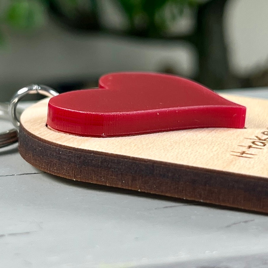 Detail shot of the Big Heart Little Minds keychain showing the dimensional red acrylic heart layered on natural maple wood.
