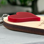 Detail shot of the Big Heart Little Minds keychain showing the dimensional red acrylic heart layered on natural maple wood.