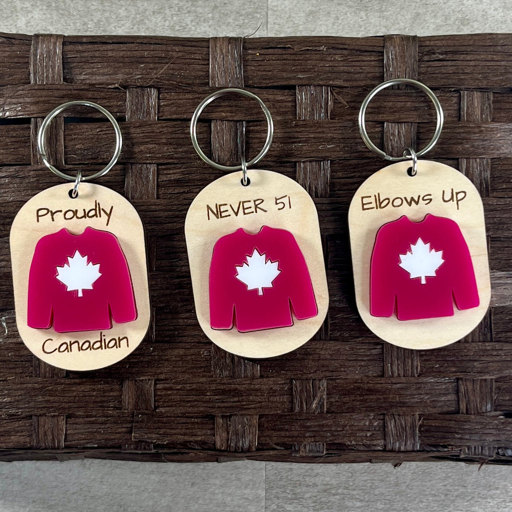 Collection of Canadian pride maple keychains showing full family of sayings with red acrylic Canadian hockey jersey