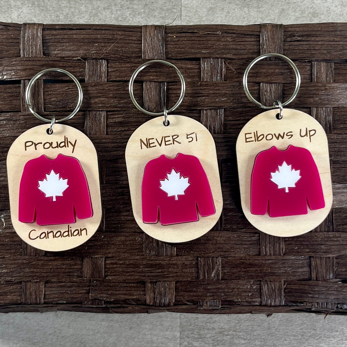 Collection of Canadian pride maple keychains showing full family of sayings with red acrylic Canadian hockey jersey