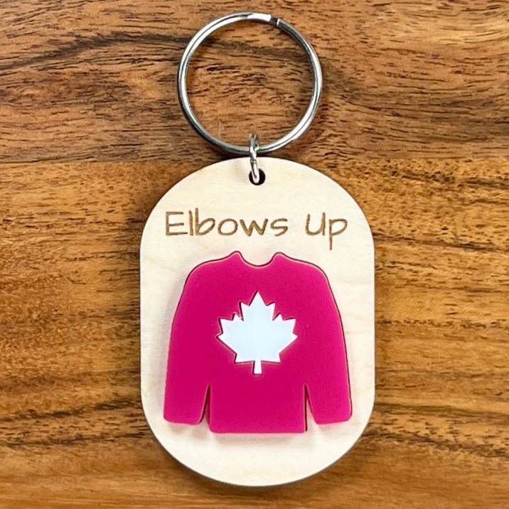 Elbows Up laser-engraved maple wood keychain with red acrylic Canadian hockey jersey on wood background
