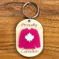 Proudly Canadian laser-engraved maple wood keychain with red acrylic Canadian hockey jersey on wood background