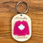 Proudly Canadian laser-engraved maple wood keychain with red acrylic Canadian hockey jersey on wood background