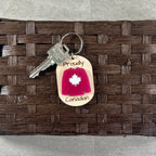 Proudly Canadian maple keychains on wicker surface with silver key ring