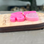 Side view close-up of an oval wooden keychain with layered pink acrylic LOVE letters, showcasing the 3D effect of the design.