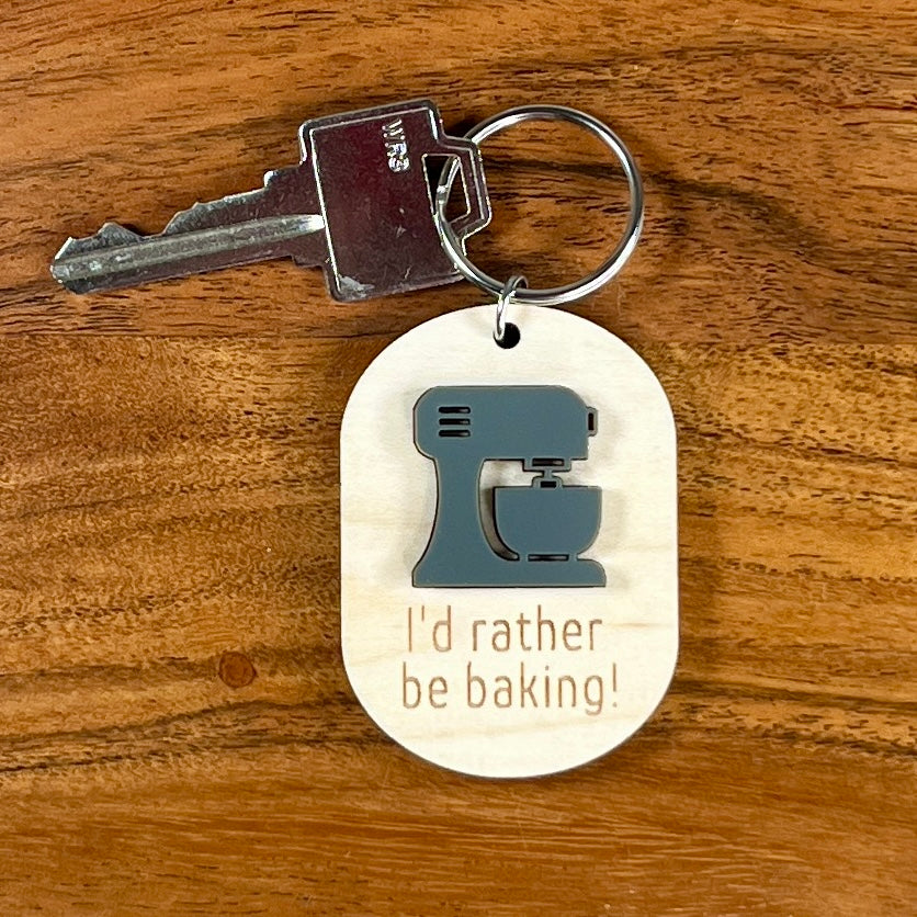 I'd Rather Be Baking maple keychain with key attached showing engraved text and grey acrylic stand mixer
