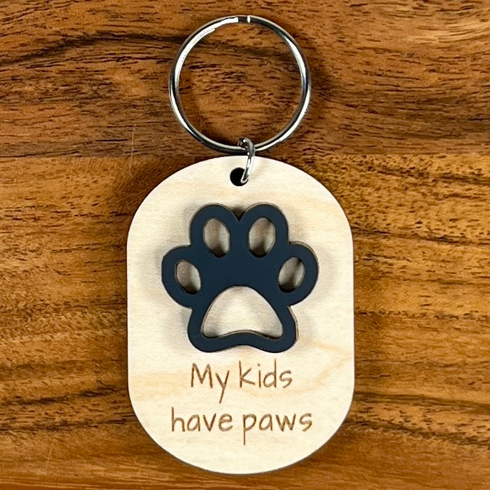 My Kids Have Paws laser-engraved maple wood keychain with black acrylic paw print on wood background