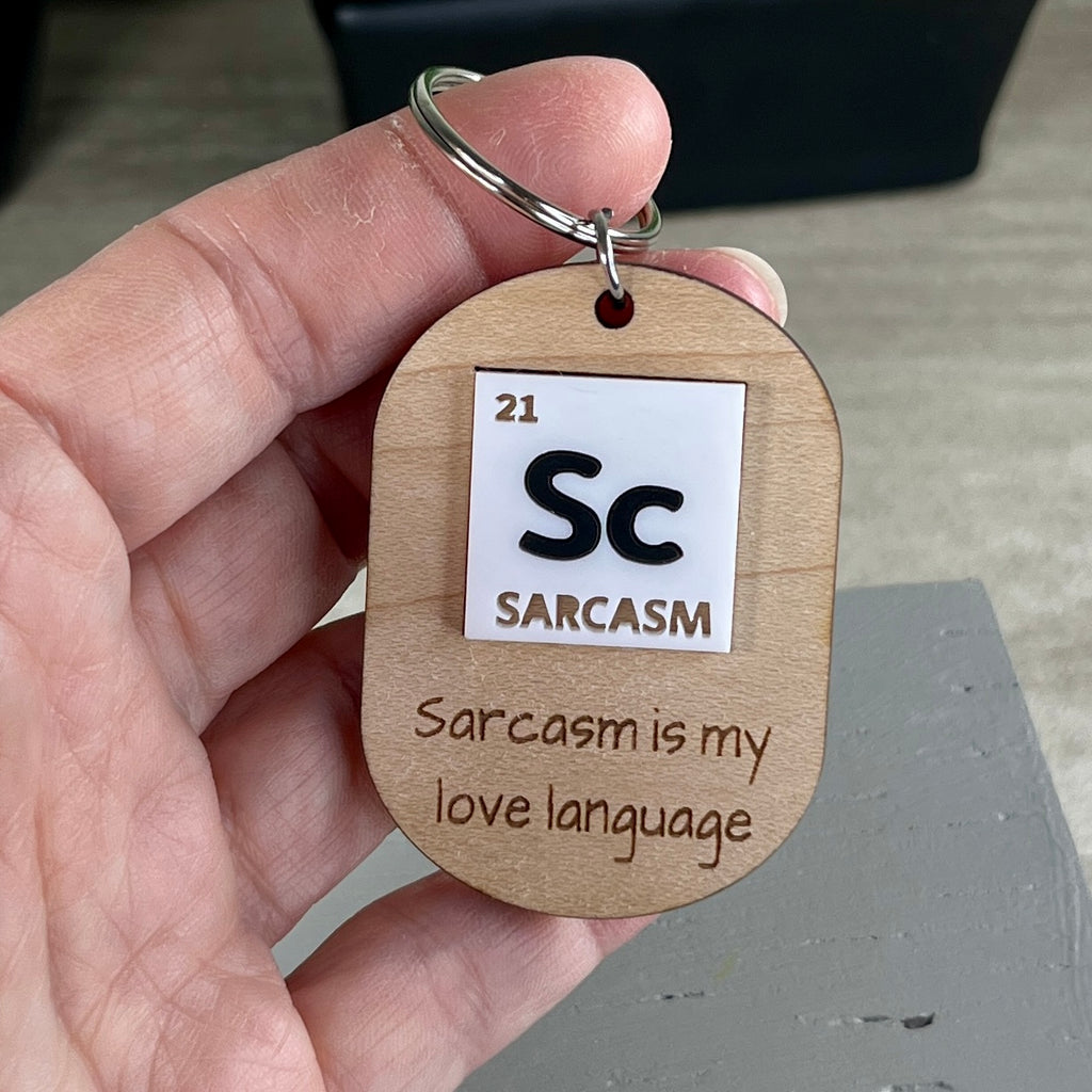 Hand holding Sc Sarcasm laser-engraved maple keychain showing periodic table acrylic detail