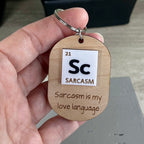 Hand holding Sc Sarcasm laser-engraved maple keychain showing periodic table acrylic detail