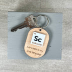 Sarcasm periodic table laser-engraved maple keychain with silver key ring on grey surface