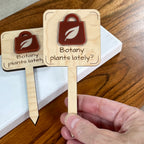 Hand holding Botany Plants Lately maple plant stakes showing rusty red and cool sand acrylic detail