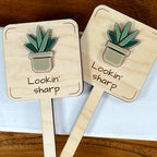 Two Lookin' Sharp maple wood plant stakes with green and taupe acrylic snake plant side by side