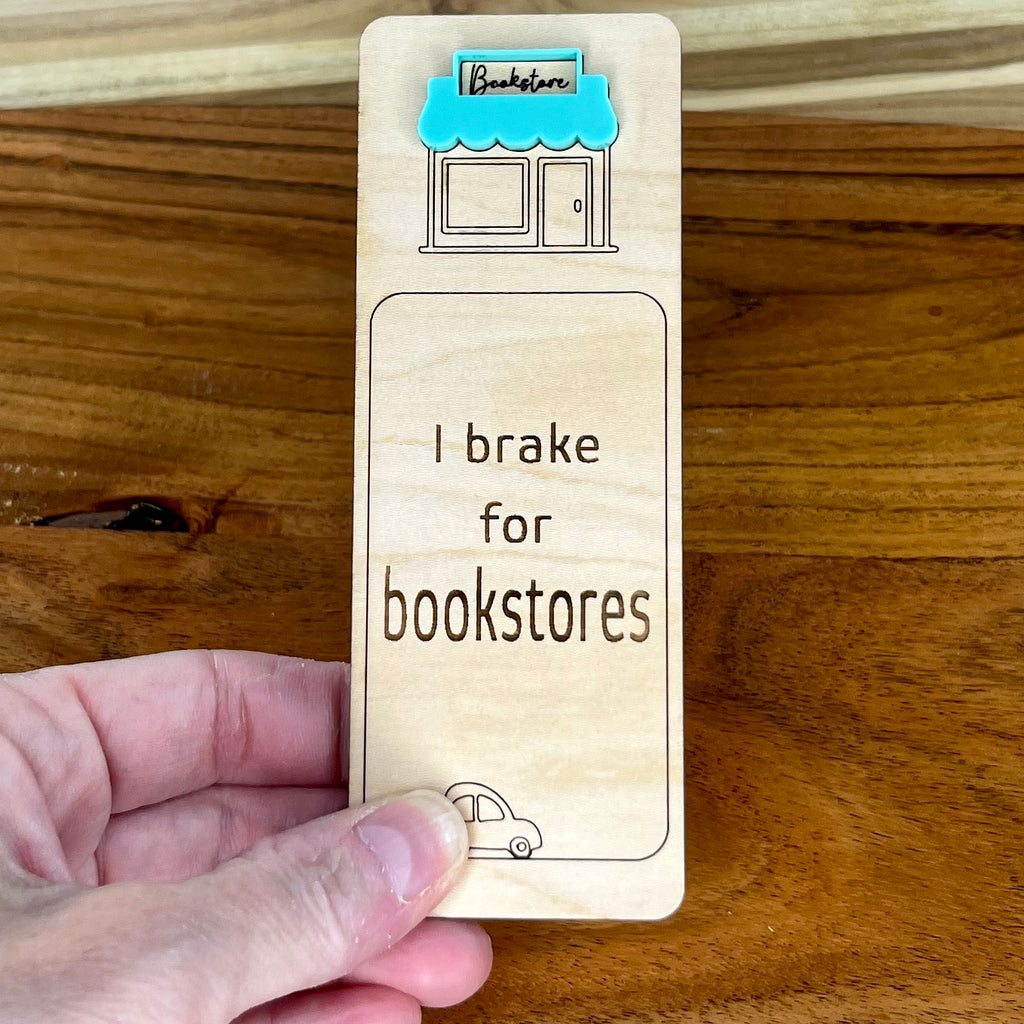 Hand holding I Brake for Bookstores birch bookmark showing mint acrylic bookstore awning detail