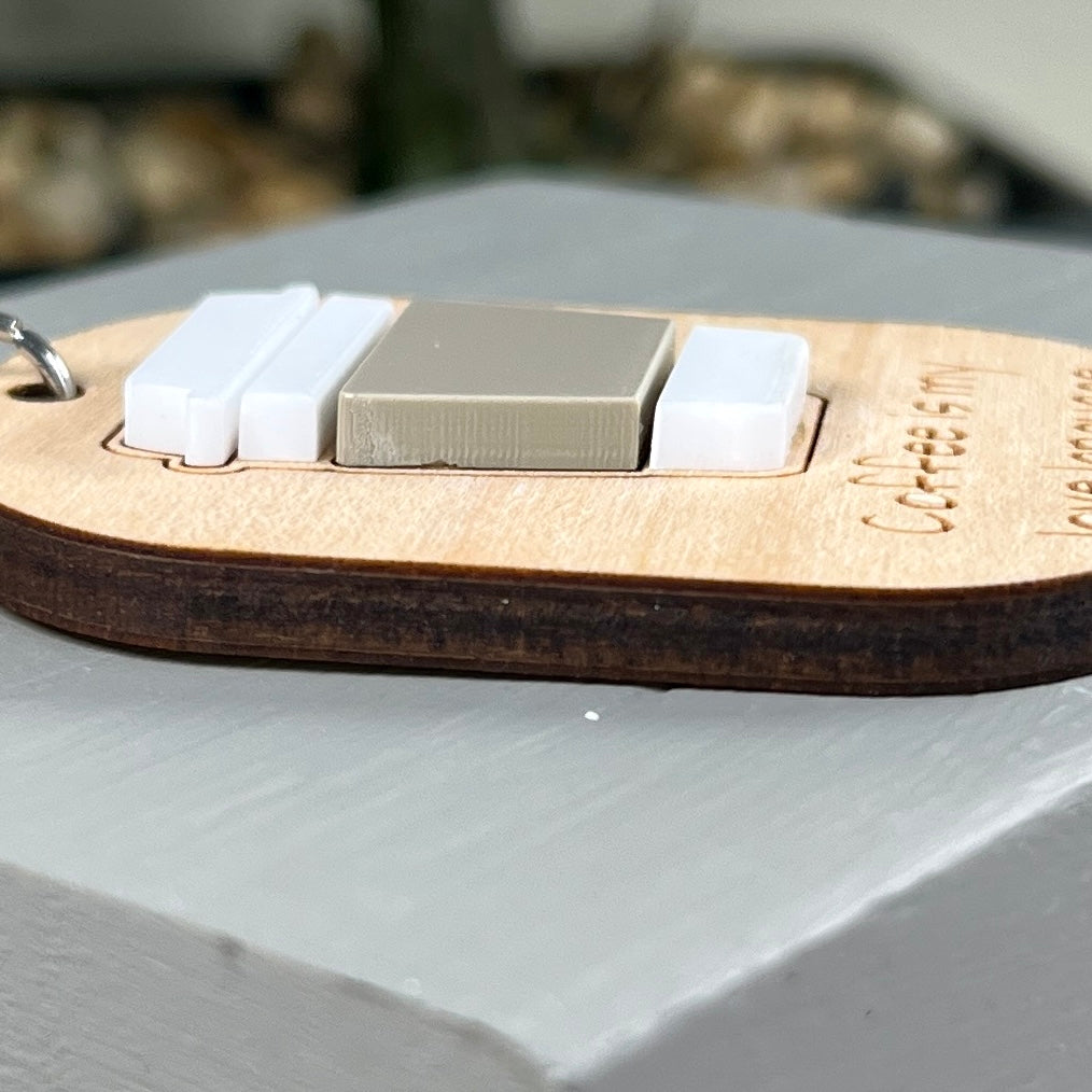 A side view close-up of a wooden laser-engraved keychain featuring an acrylic coffee cup to highlight the 3D nature of the design.