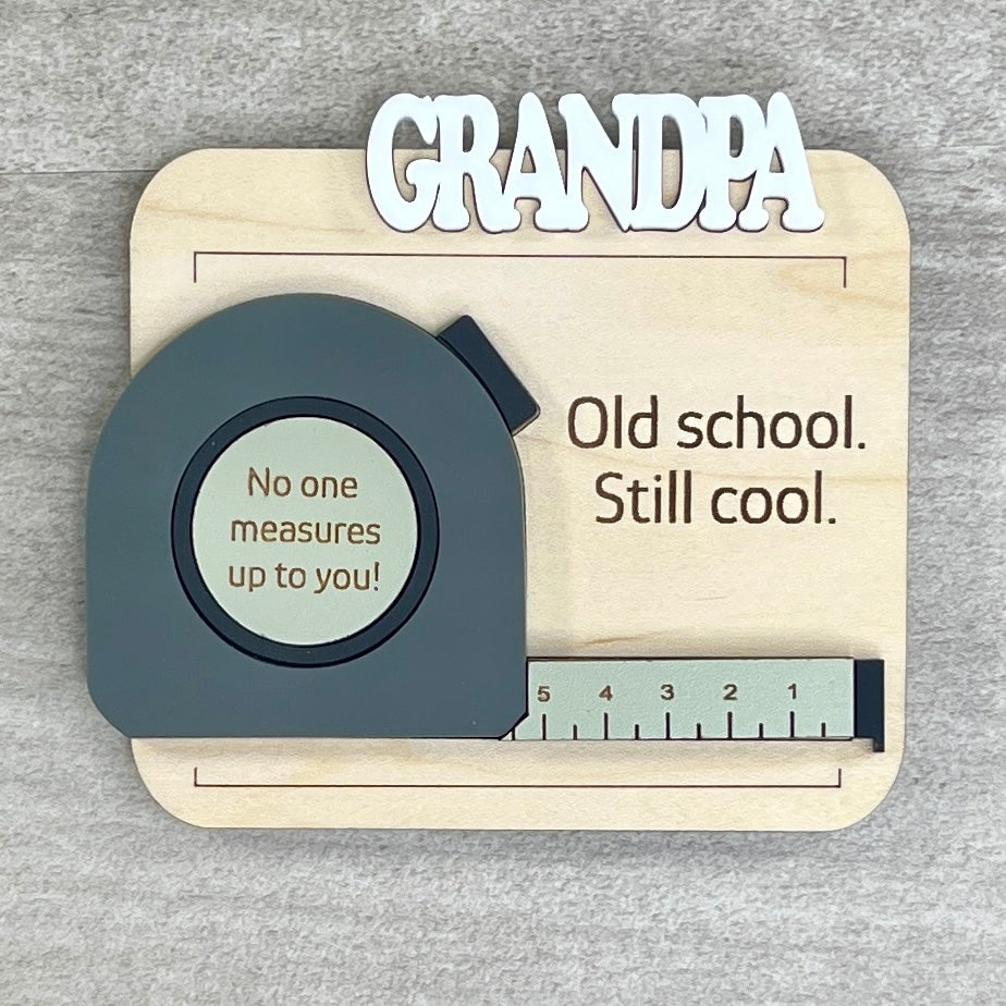 Flat lay of handcrafted tape measure fridge magnet - Old School Still Cool on natural maple