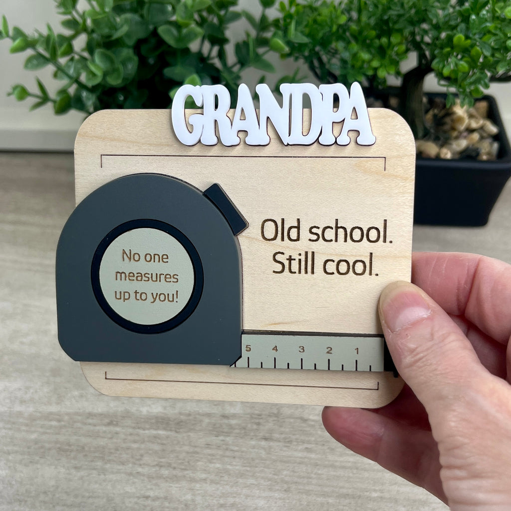 Handcrafted tape measure magnet held in hand showing personalized name and engraved message