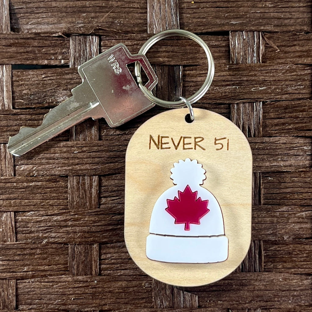 Never 51 toque maple keychains on wood surface with key ring attached showing red maple leaf detail