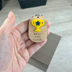 Hand holding Best Dad Ever maple keychain showing yellow acrylic trophy detail