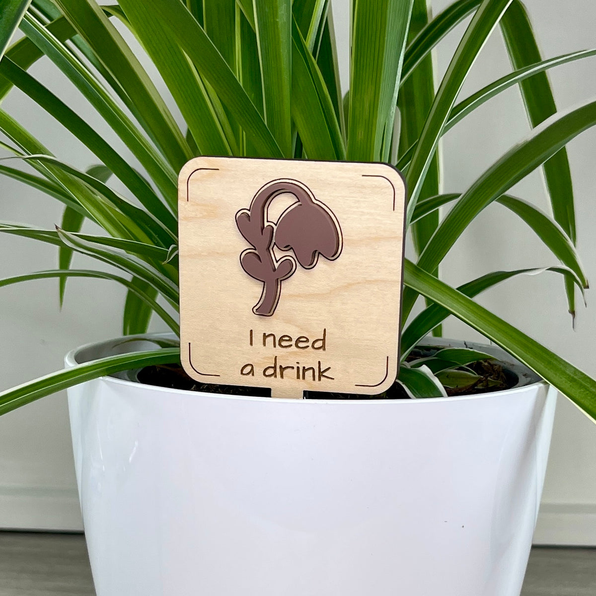 I Need a Drink maple wood plant stake with mauve acrylic wilted flower in a white pot