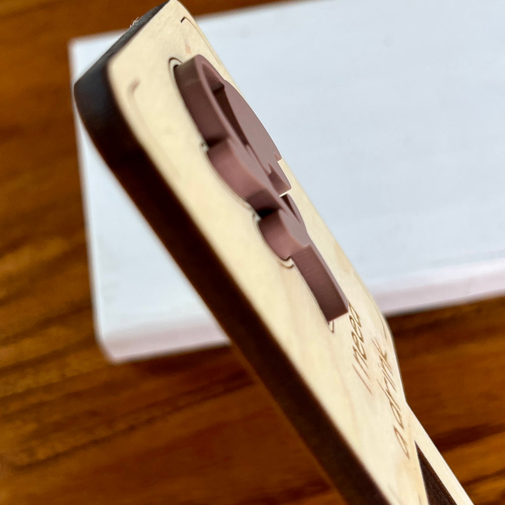 Side view of I Need a Drink plant stake showing layered maple wood and mauve acrylic depth