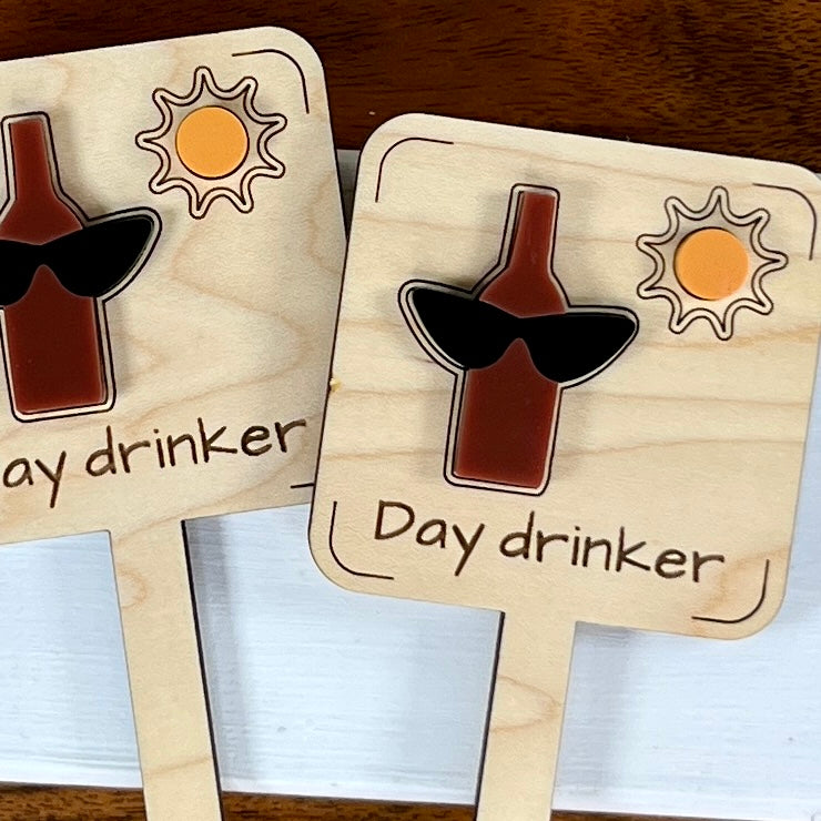 Two Day Drinker wood and acrylic plant stakes side by side showing laser-engraved wine bottle design