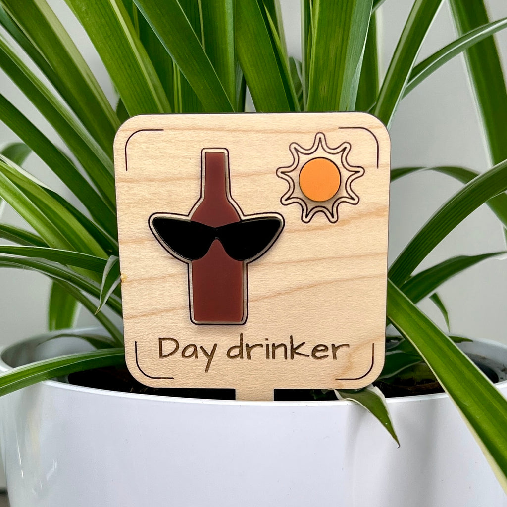 Day Drinker laser-cut maple wood and acrylic plant stake displayed in a white potted plant