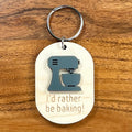 I'd Rather Be Baking laser-engraved maple wood keychain with grey acrylic stand mixer on wood background